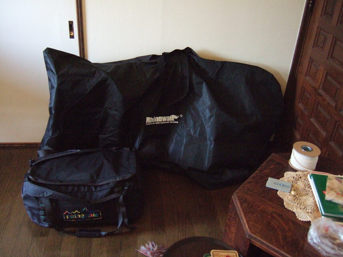 A partly disassembled bicycle wrapped in a soft cover for train transit, and a packed duffle bag.