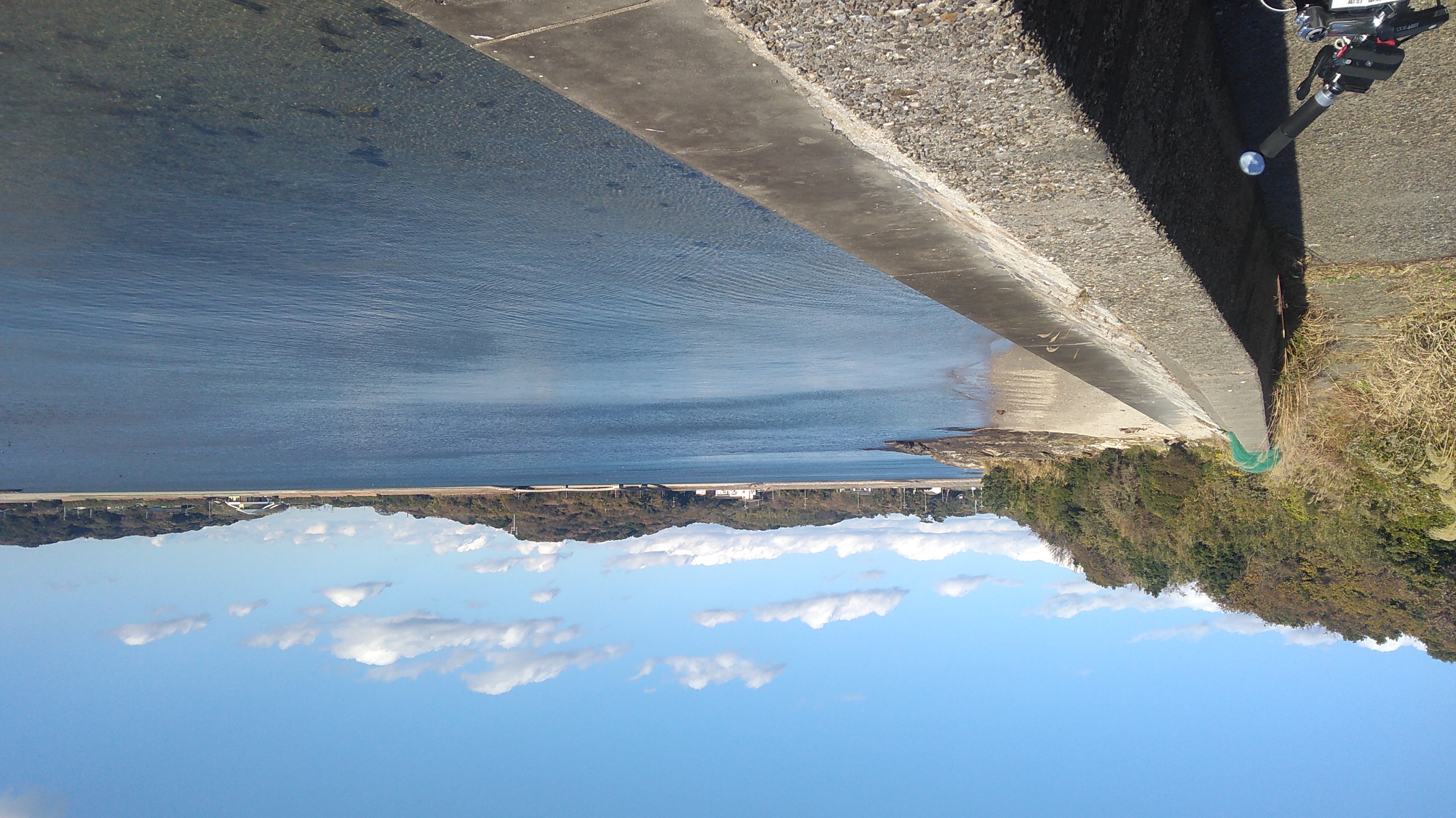 The blue waters of a lagoon under a clear sky with a smattering of distant clouds.