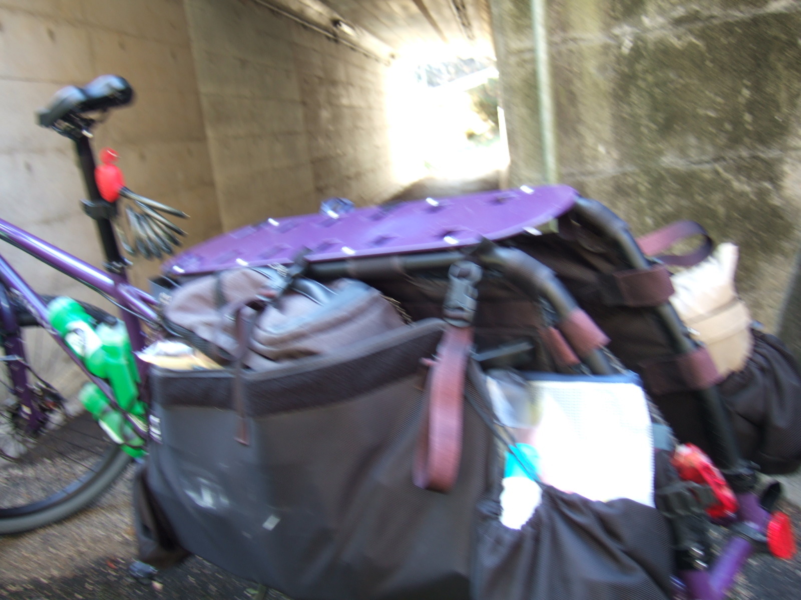 A blurry image of the back end of a cargo bike with the bright light at the end of a tunnel behind.