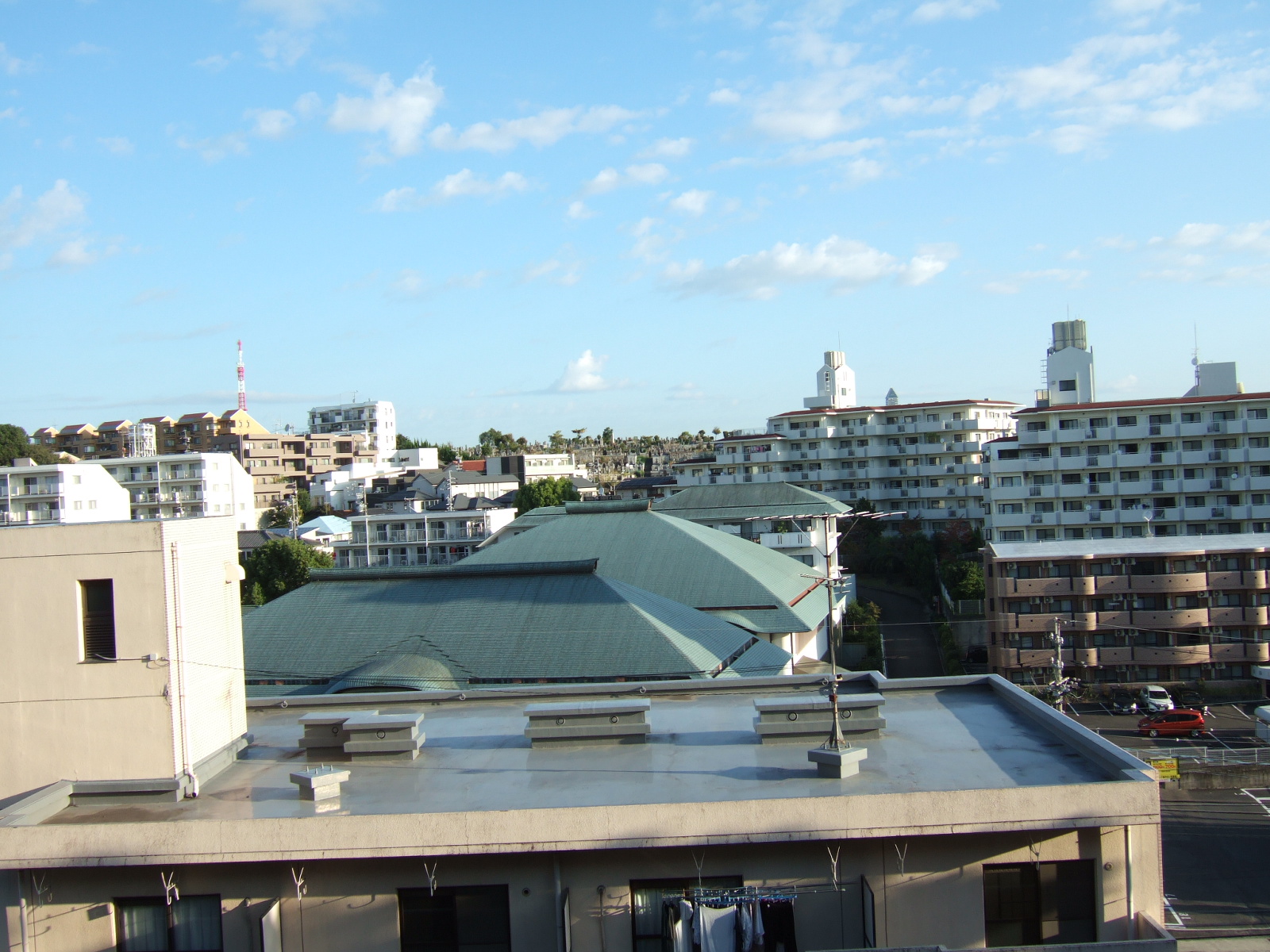 View of a skyline of square high-rise apartment blocks. The sky is clear with some small decorative clouds.