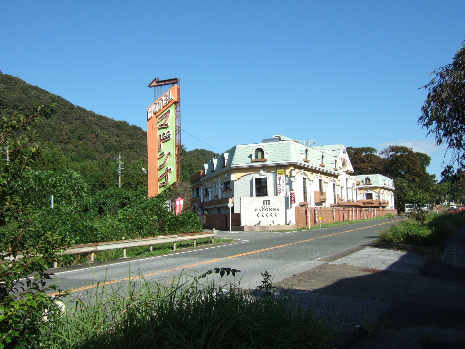 A hotel of simple modern construction with ersatz parapets. A sign reads “Hotel Madonna” HOTEL マドンナ