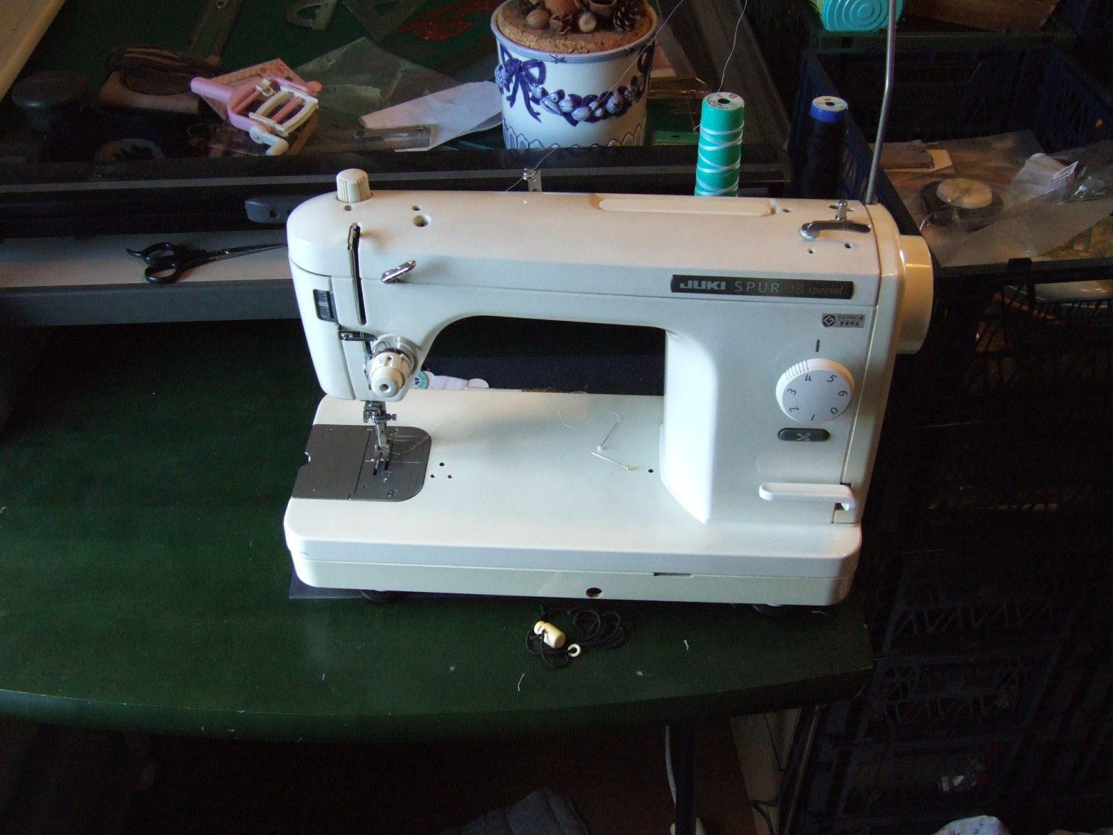 A Juki Spur 98 sewing machine set up to draw from a dwindling spool of white thread