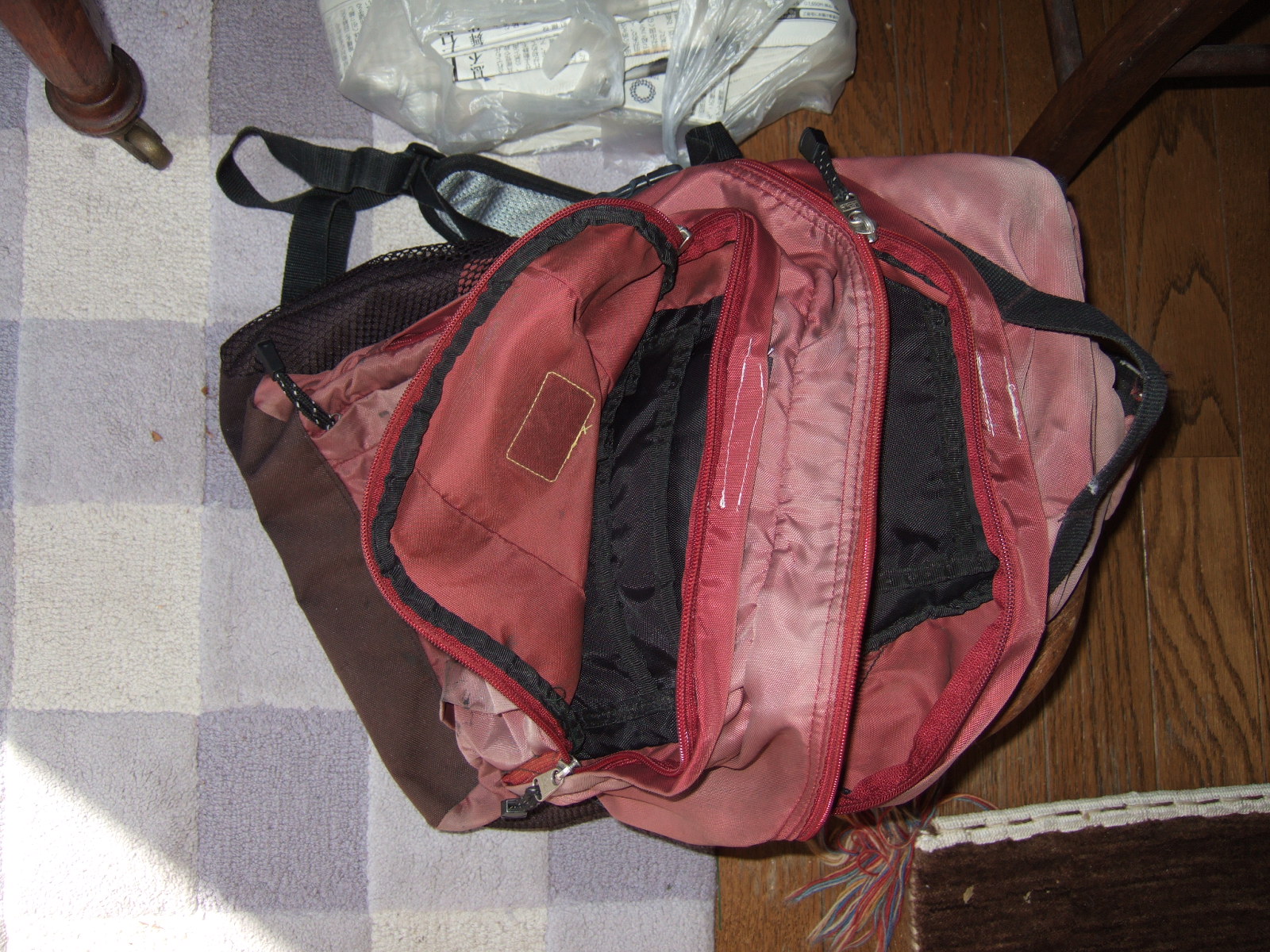 A backpack with its two large pockets zipped open, with the velcro tabs used to fold the rain flaps away from the zippers.