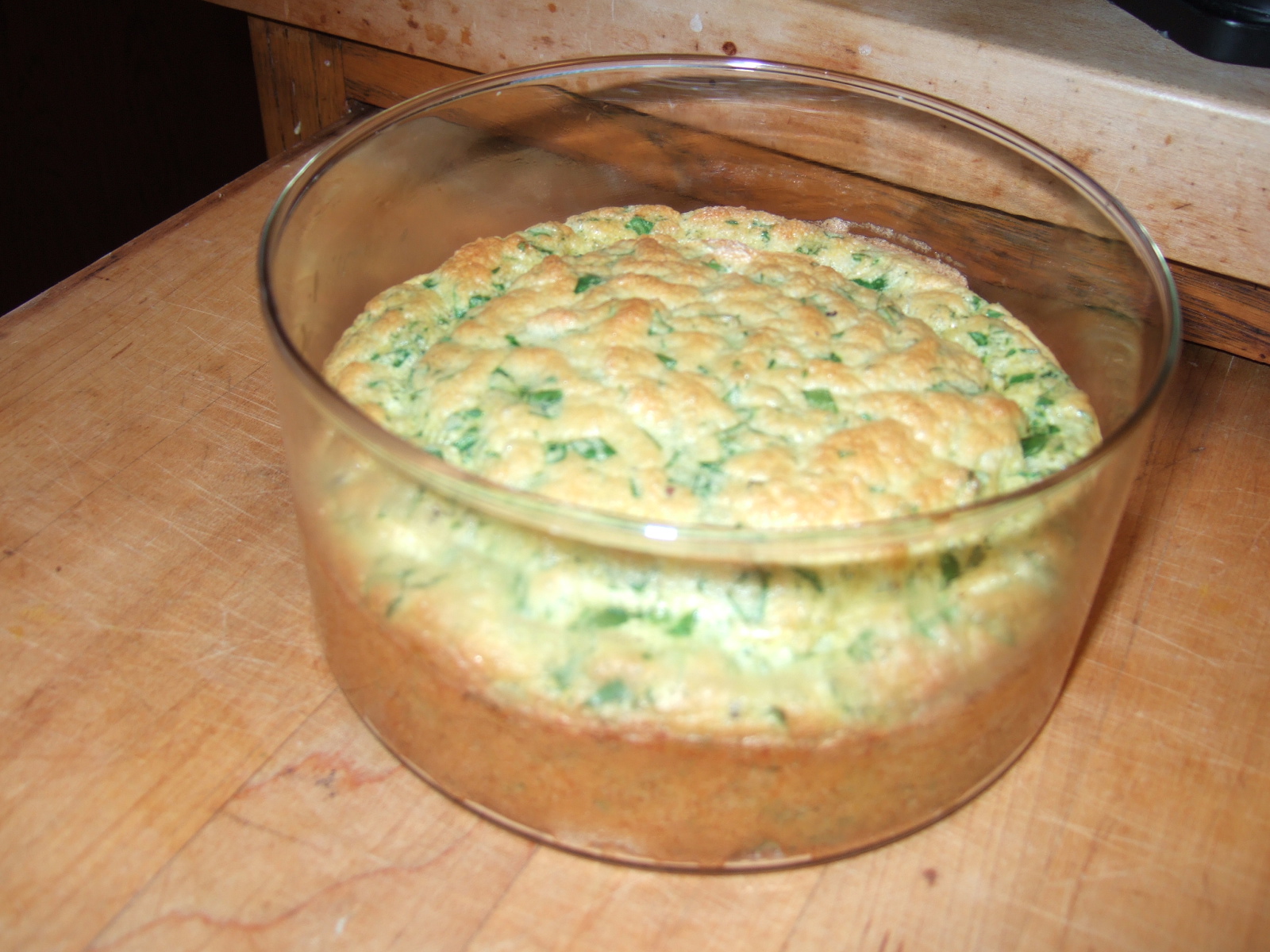 A spinach soufflé in its baking glass, fresh out of the oven.